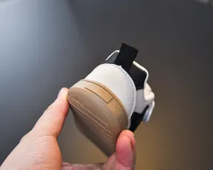 Close-up of the anti-slip rubber sole and rotary buckle on black and white kids sneakers