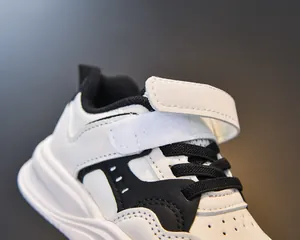 Détail de baskets en cuir noir et blanc pour enfants avec velcro et trous respirants