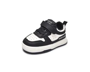 Detail view of black and white toddler sneakers with Velcro straps and breathable punch holes