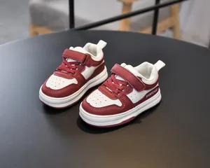 Detail of toddler sneakers featuring red and white leather with non-slip rubber soles