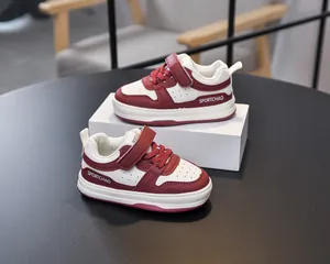 Detailed close-up of red and white toddler sneakers featuring velcro strap and faux leather