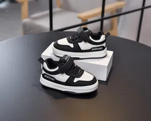 Detail of toddler sneakers featuring black and white leather with easy hook and loop closure