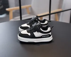 Detail of kids' black and white sneakers showing hook-and-loop straps and breathable holes