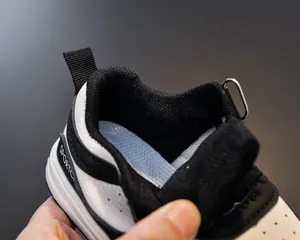 Detail of breathable light blue mesh lining and padded collar on black and white kids sneaker