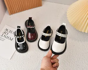 Detalle de los zapatos Mary Jane de charol para niñas con tiras de pedrería brillante