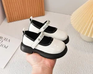 Detalle de zapatos Mary Jane beige para niñas con ribete negro y correas de pedrería