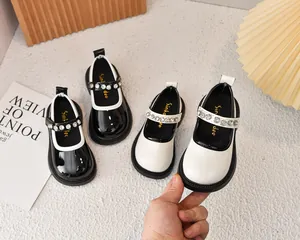 Detalle de zapatos Mary Jane de charol para niña en blanco y negro con correas de pedrería