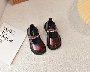 Detalle de zapatos Mary Jane de charol burdeos con correas decoradas con pedrería brillante