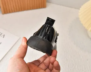 Detalle de zapatos para niñas en charol negro con suela gruesa y hebilla de diamantes