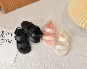 Dettagli di sandali per bambini in nero, rosa e beige con cinturini a strappo e suola morbida