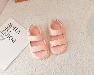Vista dettagliata dall'alto di sandali rosa per bambini con cinturini a strappo su fondo ruvido