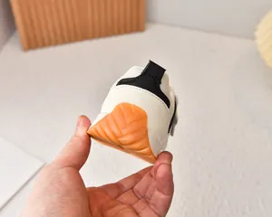 Detail of baby sneakers featuring a non-slip orange rubber sole and heel strap design