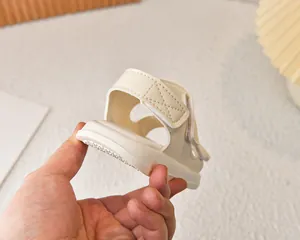 Dettaglio del sandalo beige per neonati con cinturino in velcro e suola antiscivolo