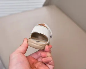 Detail of baby walking sandal with velcro strap and anti-slip rubber sole in off-white