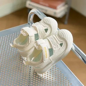 Detail view of breathable green mesh and Velcro strap on off-white toddler sandals
