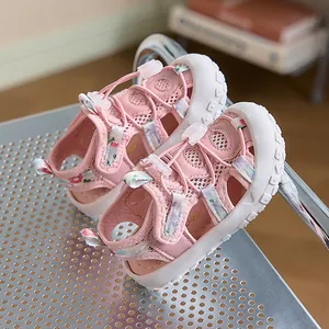 Dettaglio di sandali rosa per bambini con cinturini floreali e coulisse di chiusura regolabile