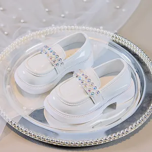 Nahaufnahme weißer Lackleder-Loafer für Mädchen mit schillernden Strasssteinen und Perlen