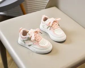 Détail de baskets enfant en cuir blanc et rose avec lacets larges et étiquette tissée