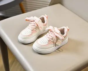 Vue détaillée de baskets enfant roses et blanches avec lacets épais et breloque