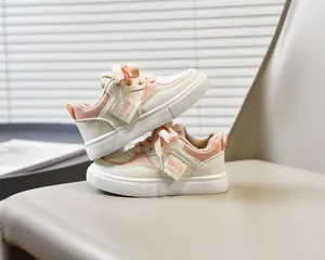 Détail de baskets enfant beige et rose avec étiquette 2025 UNU UNU sur siège en cuir