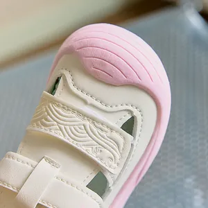 Close-up of baby sandal with soft cream leather, pink toe cap and wave texture detail