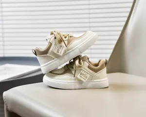 Détail de baskets blanches pour enfants avec lacets marrons et écussons latéraux
