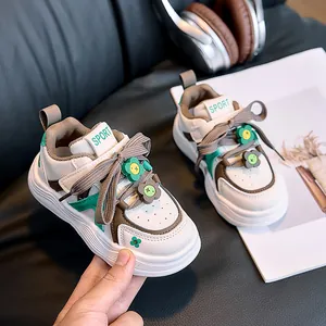 Detail of kids white leather sneakers with green accents and flower lace charms