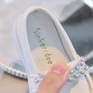Detailaufnahme weißer Prinzessinnen-Schuhe mit schillernden Perlen und goldenem Logo-Print