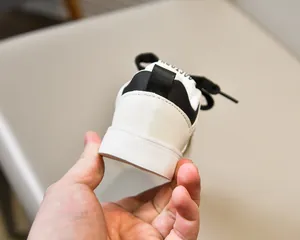 Détail du talon en cuir synthétique noir et blanc et de la languette sur baskets enfant