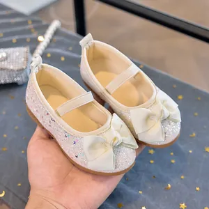 Close-up of white sequin Mary Jane shoes for girls featuring a ribbed bow and elastic strap
