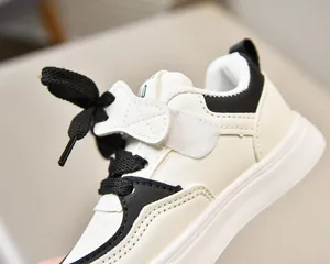 Détail de baskets blanches pour enfants avec fermeture velcro et accents noirs