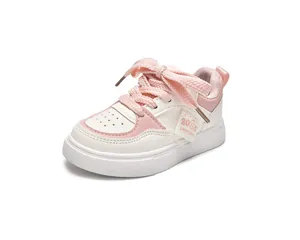 Détail de chaussures enfant blanches et roses avec étiquette 2025 et lacets tissés