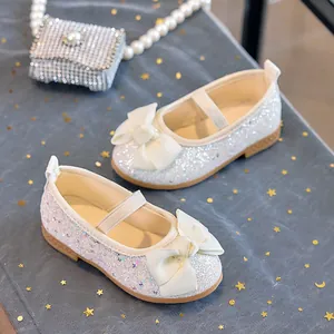 Detail of white sequin Mary Jane shoes with satin bow and elastic strap for girls