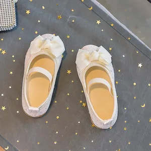 Close-up of white sequined girls Mary Jane shoes with large grosgrain ribbon bow