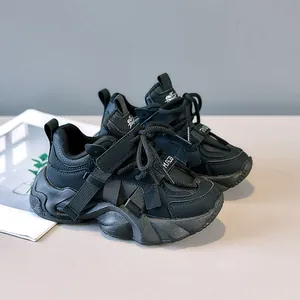 Detail of kids black chunky sneakers with faux leather texture and outdoor velcro closure