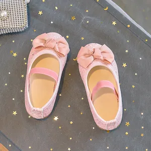 Close-up of pink glitter princess shoes with satin bow and elastic strap for girls