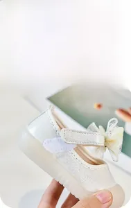 Détail de chaussures bébé Mary Jane blanches scintillantes avec nœud en maille et semelle