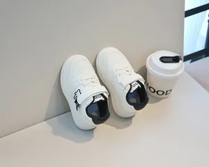 Dettaglio di sneaker in pelle bianca per bambini con motivo orso e chiusura a strappo