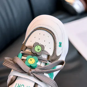Detailed close-up of child's white sneaker with floral charms and breathable toe cap