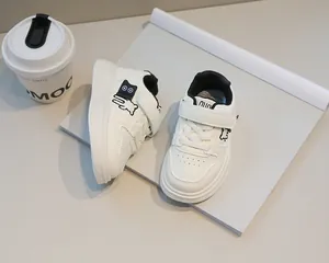 Dettaglio di sneaker in pelle bianca per bambini con orsetto nero e chiusura a strappo