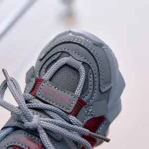Detail of gray kids dad sneaker showing leather mesh texture and burgundy accents