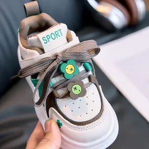 Close-up of kids white sneakers with brown-green panels and cute flower lace buckle