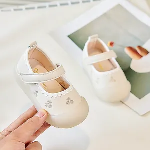 Details von cremefarbenen Baby-Lauflernschuhen mit Kirschstickerei und Klettverschluss