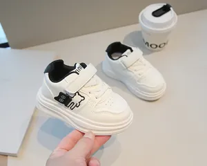 Dettaglio scarpe bimbi in pelle bianca con ricamo a orsetto e chiusura a strappo