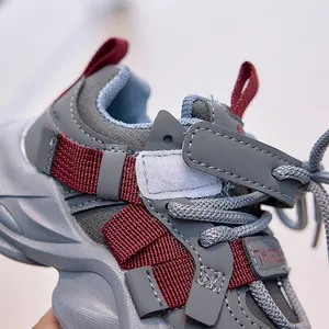 Close-up of kids leather sneakers showing grey stitching and deep red ribbon detail