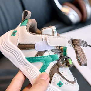 Close-up of kids' beige leather sneakers with green flower detail and velcro straps