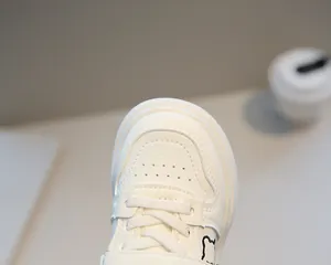 Dettaglio di scarpe da ginnastica bianche per bambini con fori e ricamo di un piccolo orso