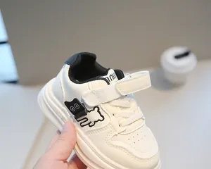 Dettaglio di scarpe da ginnastica in pelle per bambini bianche con ricamo a forma di orso