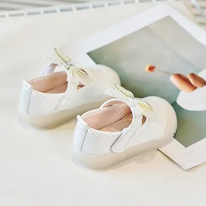 Détail de chaussures Mary Jane blanches avec nœud en dentelle, perles et semelle