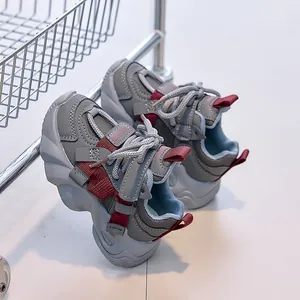 Detail of gray kids sneaker with red accents and convenient hook and loop strap